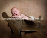Newborn baby boy in wooden toy aeroplane